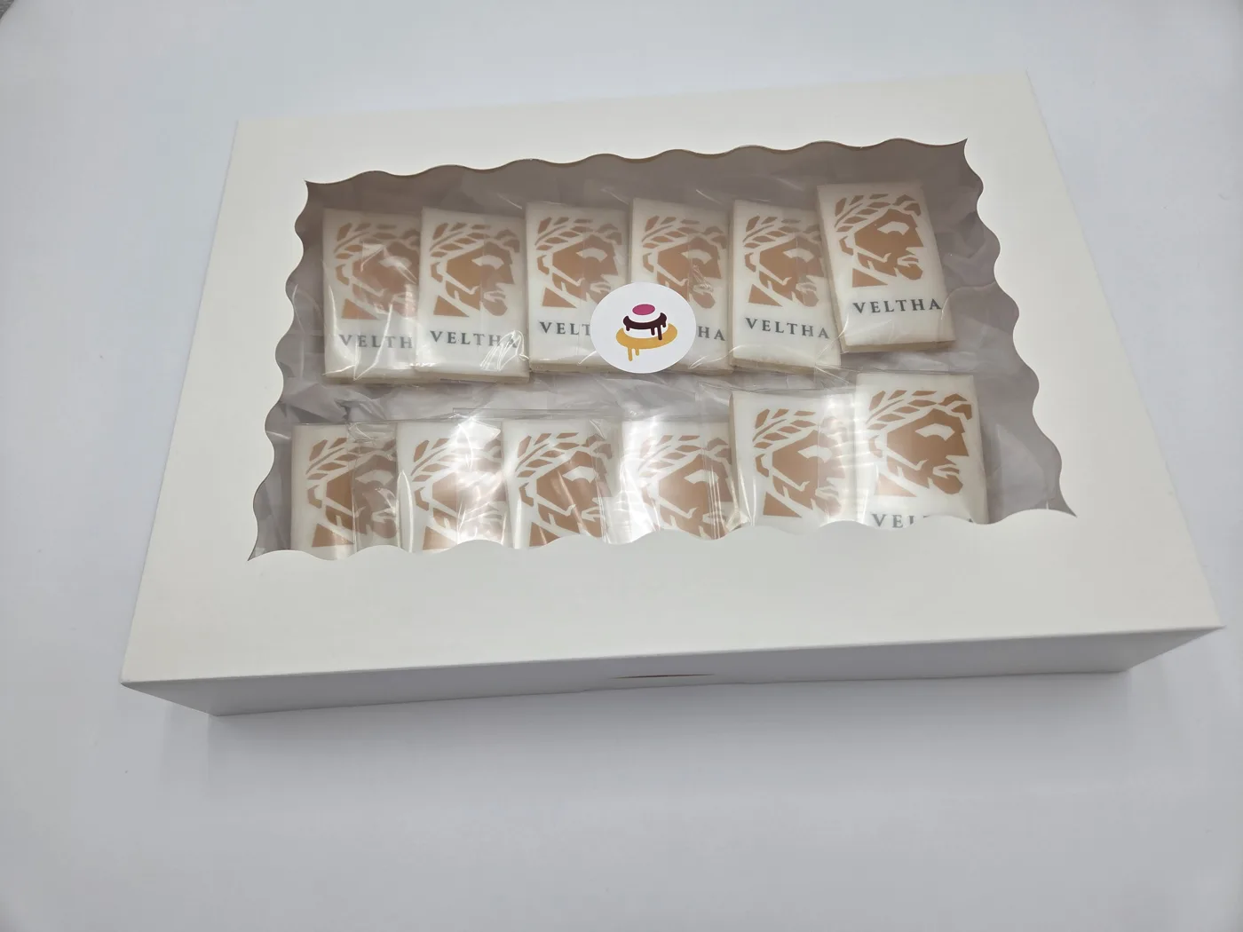 A dozen printed image cookies individually wrapped in a ribboned gift box